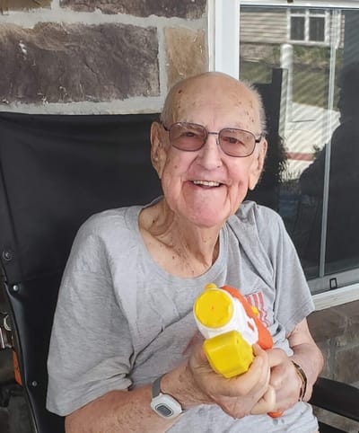 Elderly man smiling with a toy water gun