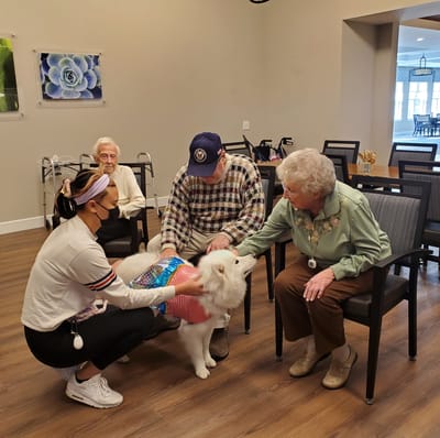 Residents interacting with a therapy dog in a social area.