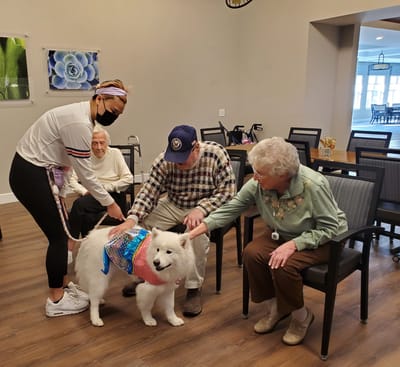 Residents interacting with a therapy dog and staff member.