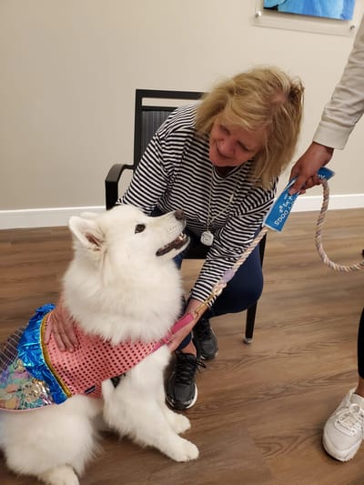 Resident interacting with a therapy dog indoors.