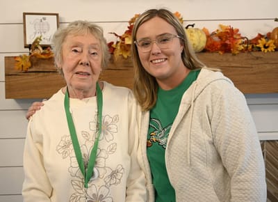 Resident and staff member posing together indoors.