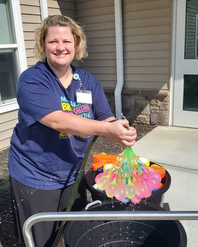 Staff member engaging residents with water balloons.