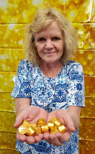 Resident holding golden candies with a festive background.