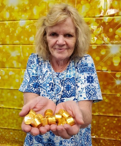 Resident holding golden candies with a festive backdrop.
