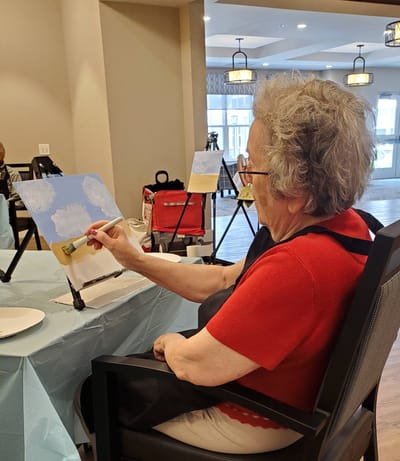 Elderly resident painting indoors during an activity
