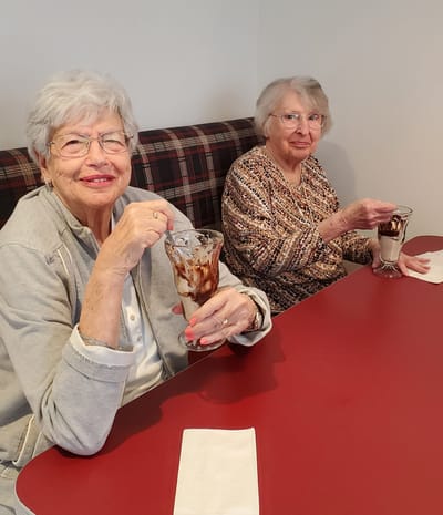 Two elderly women enjoying ice cream sundaes