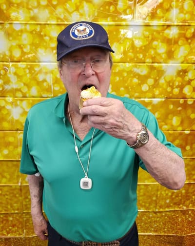 Elderly man enjoying a dessert treat indoors.