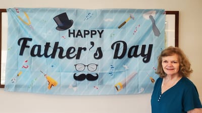 Resident celebrating Father's Day with banner.