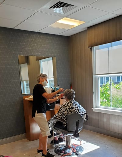 Resident receiving hair services in a salon setting.