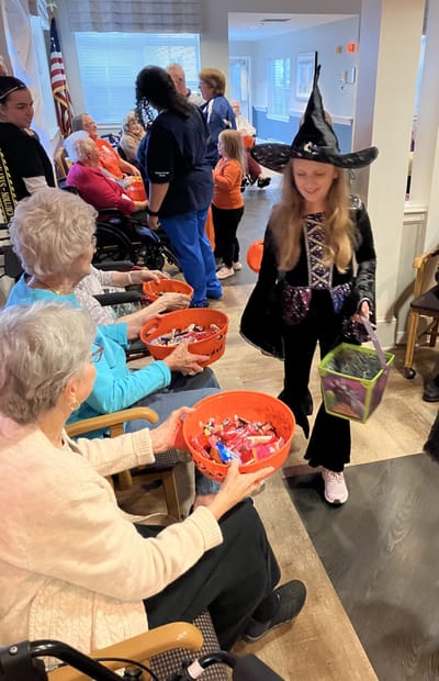Residents celebrating Halloween with a costumed child.