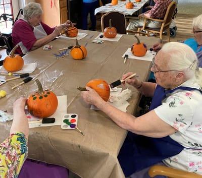 Residents painting pumpkins during an activity.