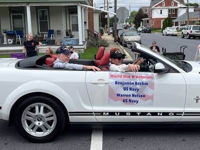 WWII veterans celebrating in a parade convertible