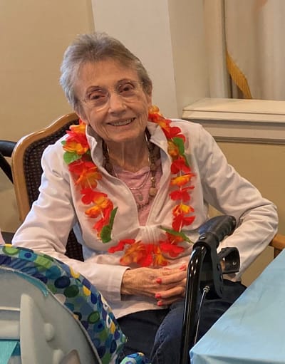 Senior woman smiling with a flower necklace.