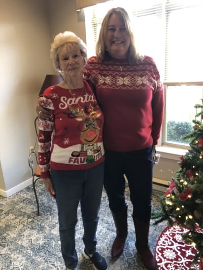 Residents wearing festive sweaters by a Christmas tree