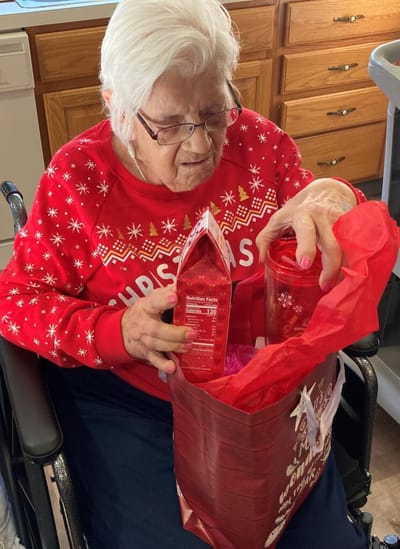 Senior woman enjoying a gift with festive decorations.