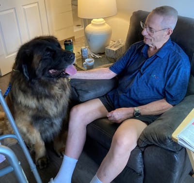 Senior man with a large dog in a cozy chair.