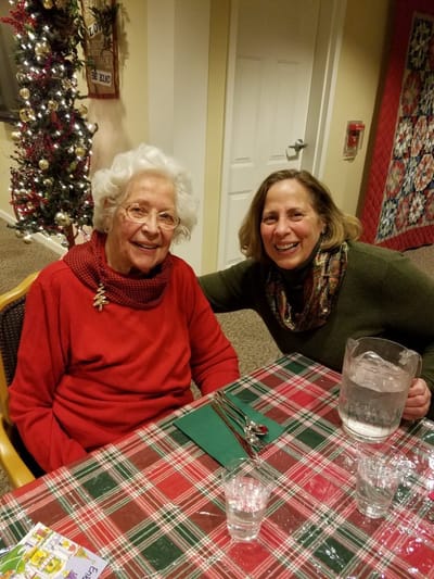 Senior resident and staff member at dining table