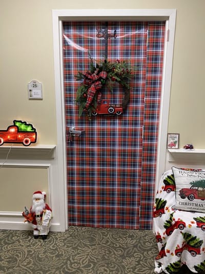 Festively decorated door with plaid wrapping and holiday decor.