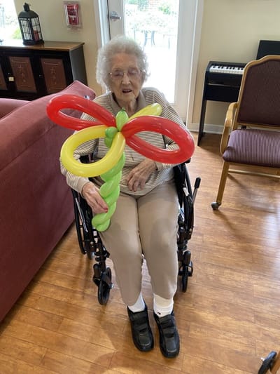 Resident holding a balloon flower in a common area.