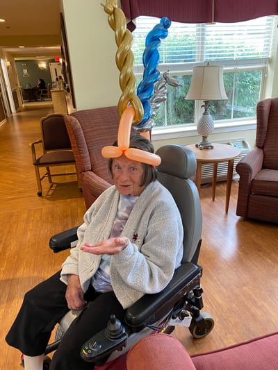 Resident with a balloon hat in a common area