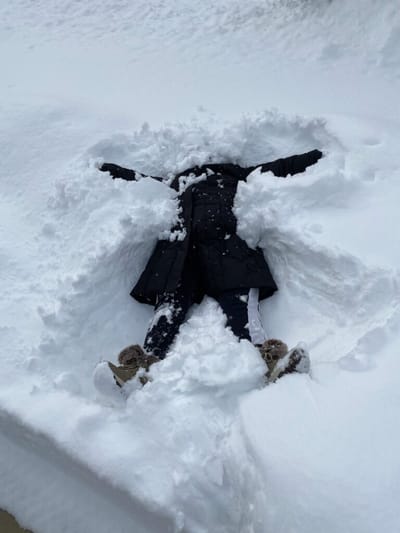 Person lying in a snowbank, making snow angels.