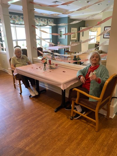 Two elderly residents celebrating in a decorated common area.
