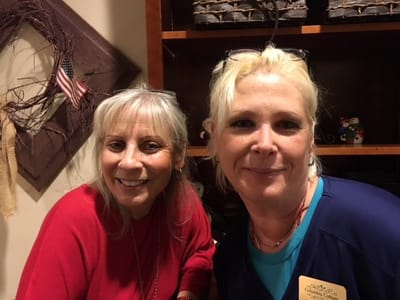 Two staff members smiling together in a facility setting.