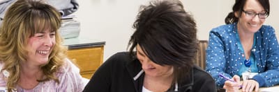 Staff members interacting and smiling at a table
