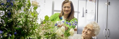 Staff member arranging flowers with a resident.