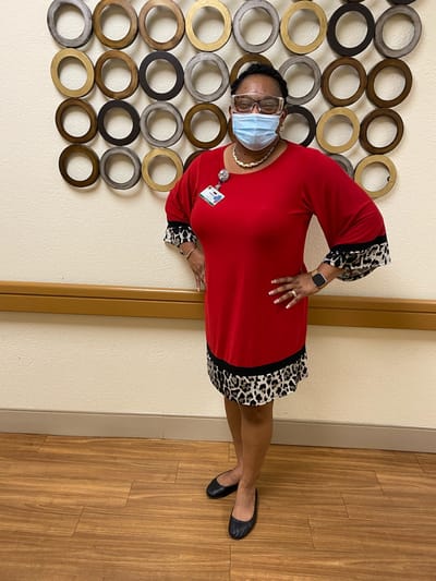 Staff member in red dress standing indoors.