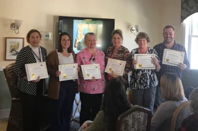 Staff members posing with certificates in a common area