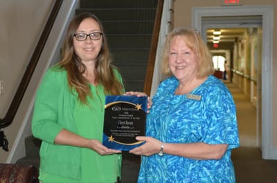 Two staff members presenting an award in a hallway