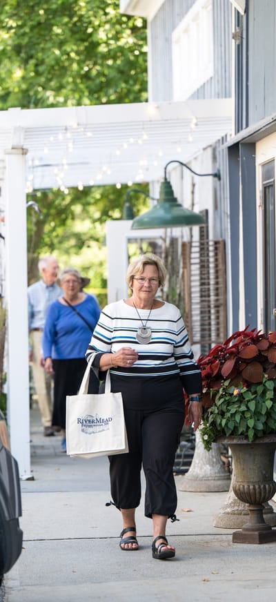 Resident walking with a tote bag along a path