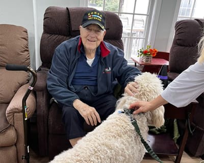 Resident with a dog in a cozy chairs area