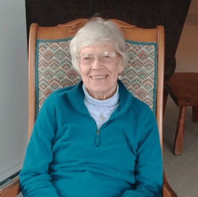 A smiling elderly woman sitting in a chair in a cozy interior