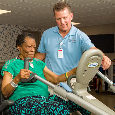 Staff assisting a resident with exercise equipment
