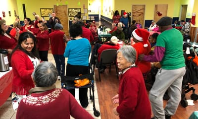 Residents and staff celebrating together in a lively activity room