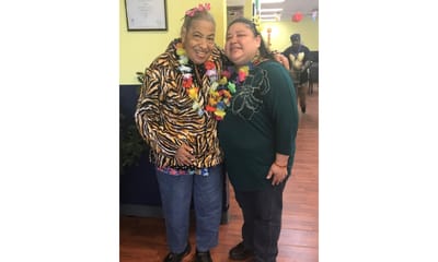 Two residents celebrating with leis in a festive interior