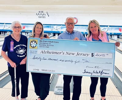 Participants holding a large check for Alzheimer's charity