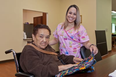 An elderly resident with a caregiver in an interior setting