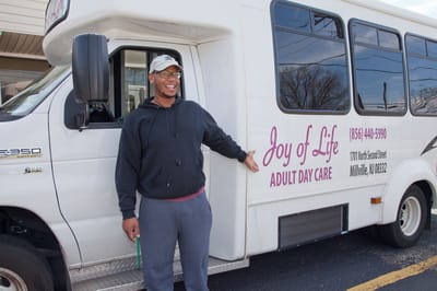 A smiling staff member by the facility transport van