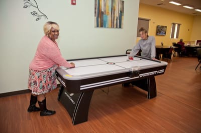 Residents enjoying air hockey in an interior activity room