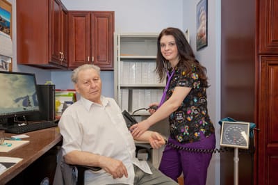 Healthcare professional assisting a senior with blood pressure check
