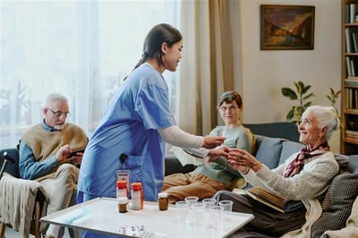 A caregiver handing medication to a resident in a common area