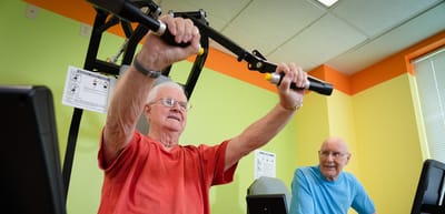Residents exercising in a well-lit gym area