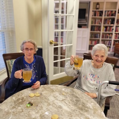Two residents toasting with drinks at a round table