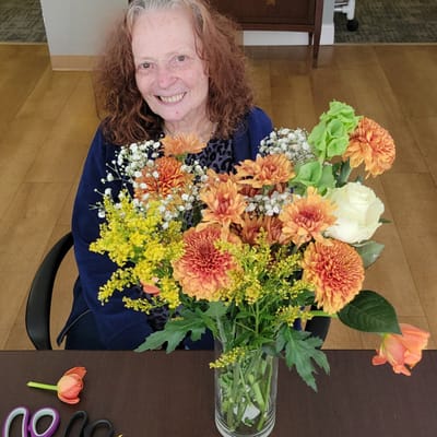 A resident arranging vibrant flowers at a table