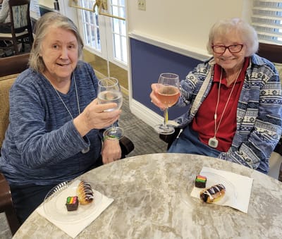 Two residents toasting with drinks at a table