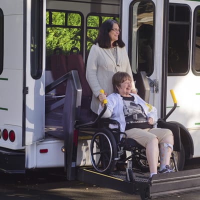 A woman in a wheelchair exiting a facility van
