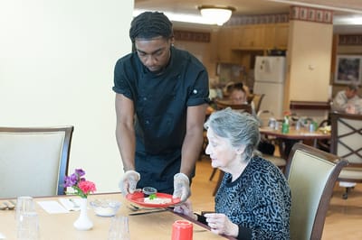 Staff serving food to a resident in the dining room